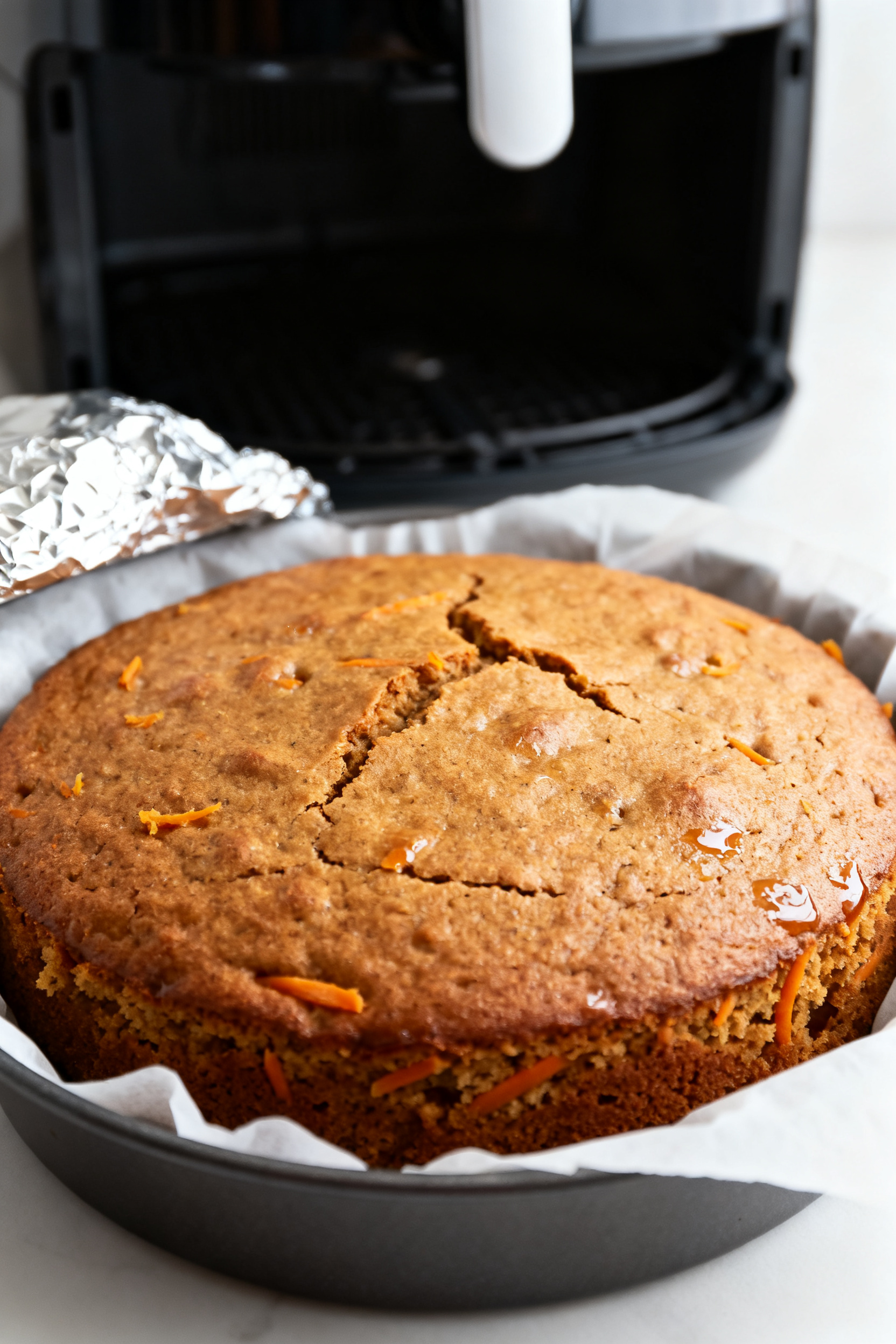 Close-up detail shot: A freshly air-fried carrot cake still in a 6-inch round pan lined with parchme